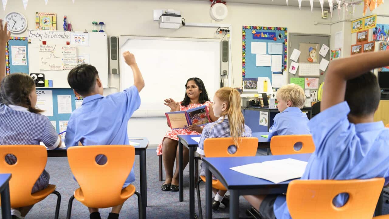 School children in classroom listening to teacher