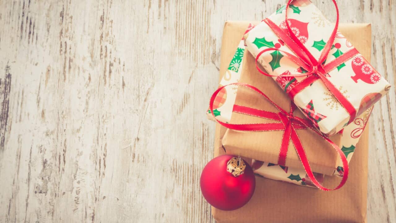 Stack of Christmas presents and red Christmas bauble on wood