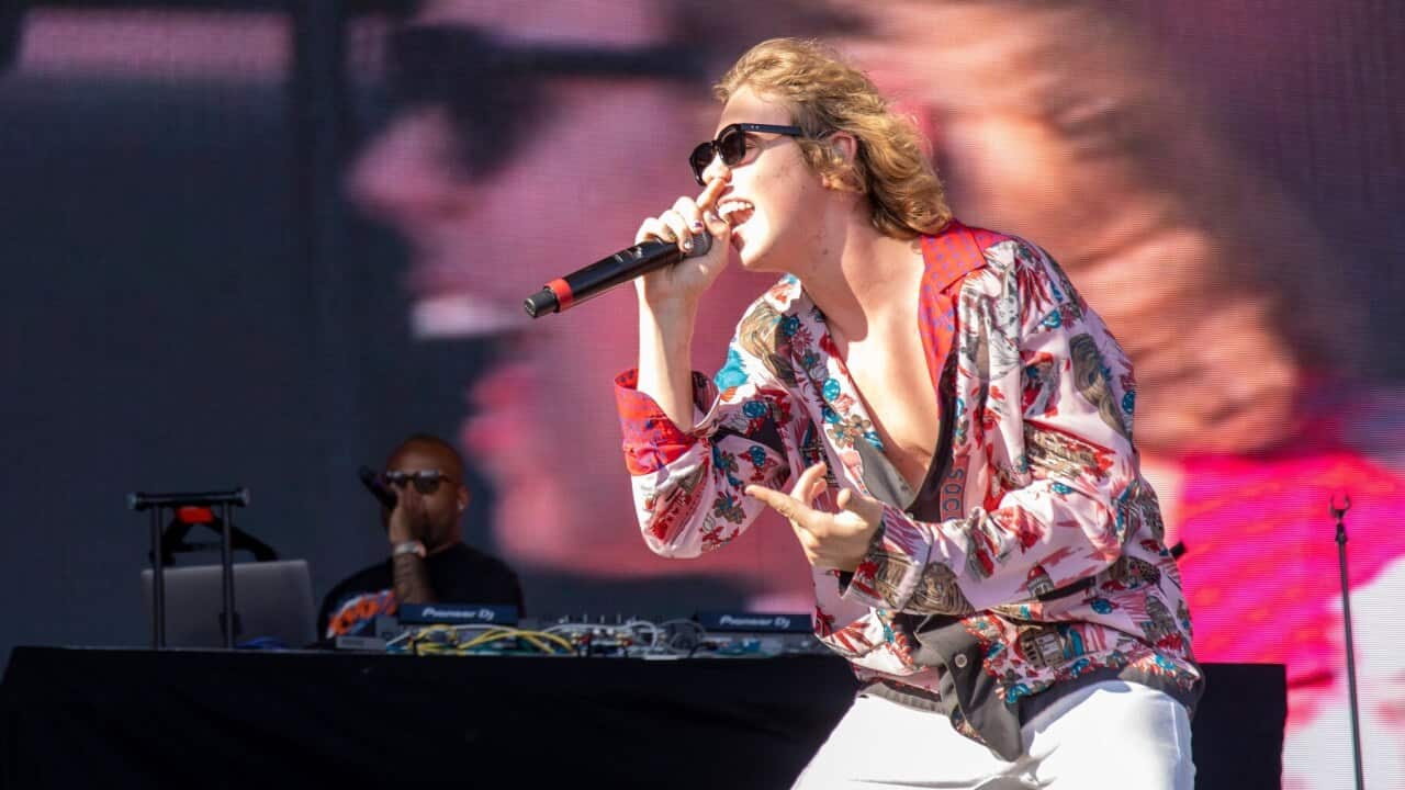 The Kid Laroi performs on stage with dark glasses and colourful print shirt