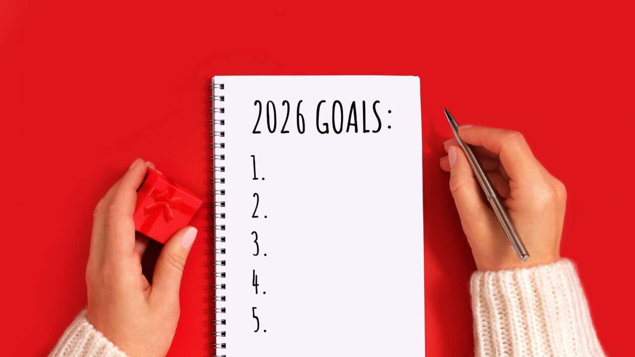 Merry Christmas and Happy New Year invitation, greeting card. New Goals concept. Woman is Writing New Year goals 2026 in winter holidays celebration.