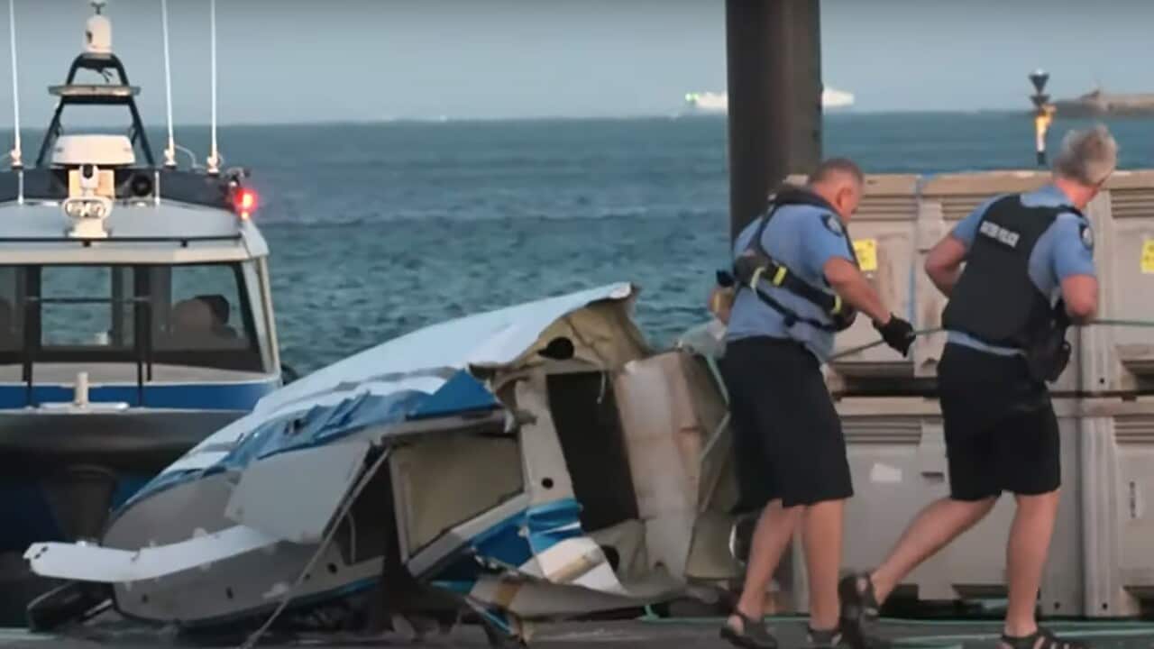 Police standing near part of a destroyed plane that has been brought ashore.