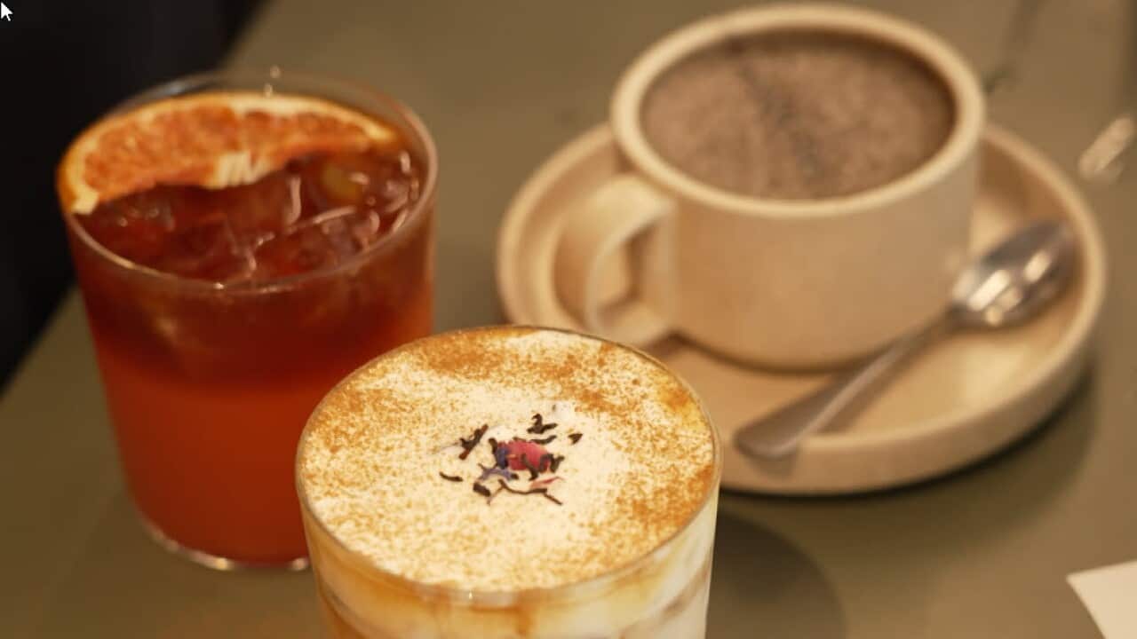 Three drinks sit on a tray, a traditional coffee in a cup, a grapefruit drink and a crema latte.