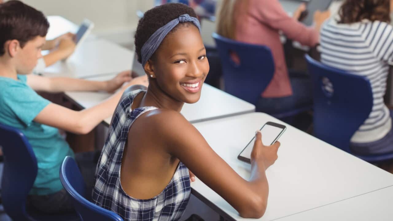 Student holding mobile phone in classroom