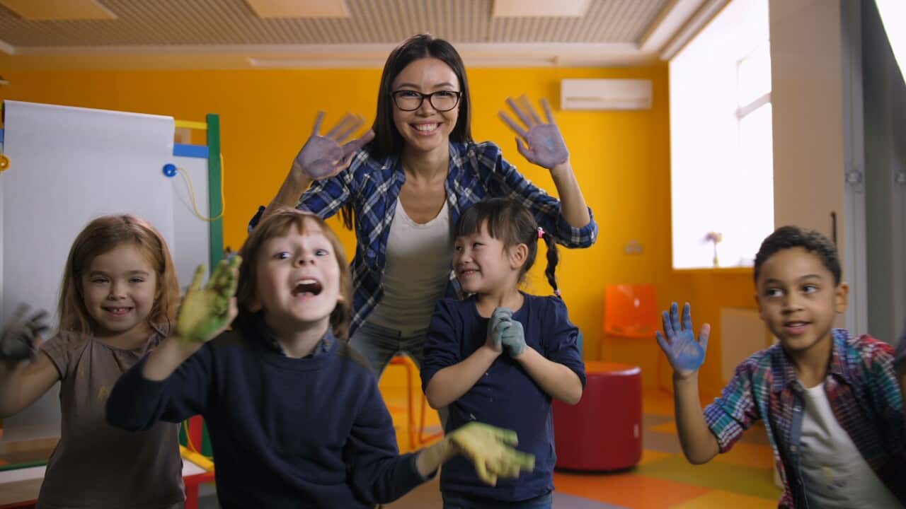 happy-funny-multicultural-children-with-smiling-teacher-showing-their-hands-stained-wi-SBI-351244543.jpg