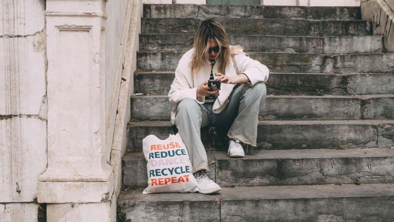 A woman sits on a staircase and looks into her smartphone