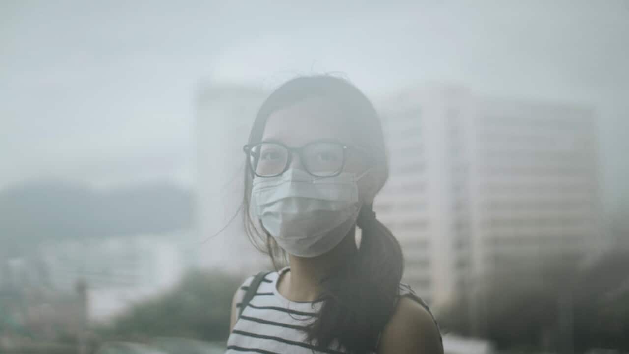 Young woman wearing protective face mask outdoors due to the polluted air