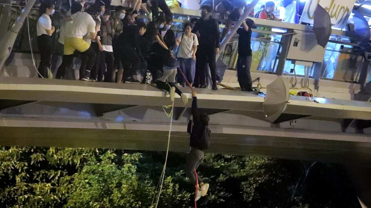 Protestors use a rope to lower themselves from a pedestrian bridge to waiting motorbikes in order to escape from Hong Kong Polytechnic University.