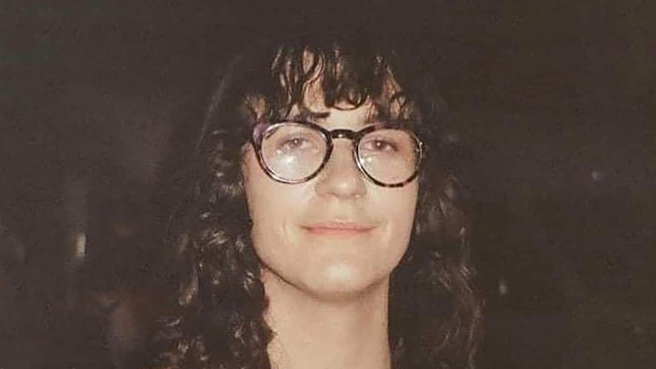 A woman with brown hair wearing glasses and a grey top