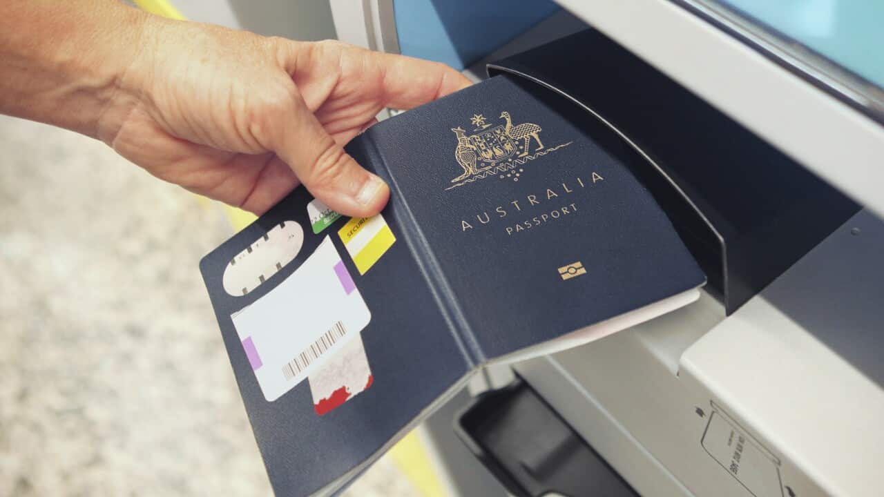 An electronic check-in counter with a person placing an Australian passport to be scanned.