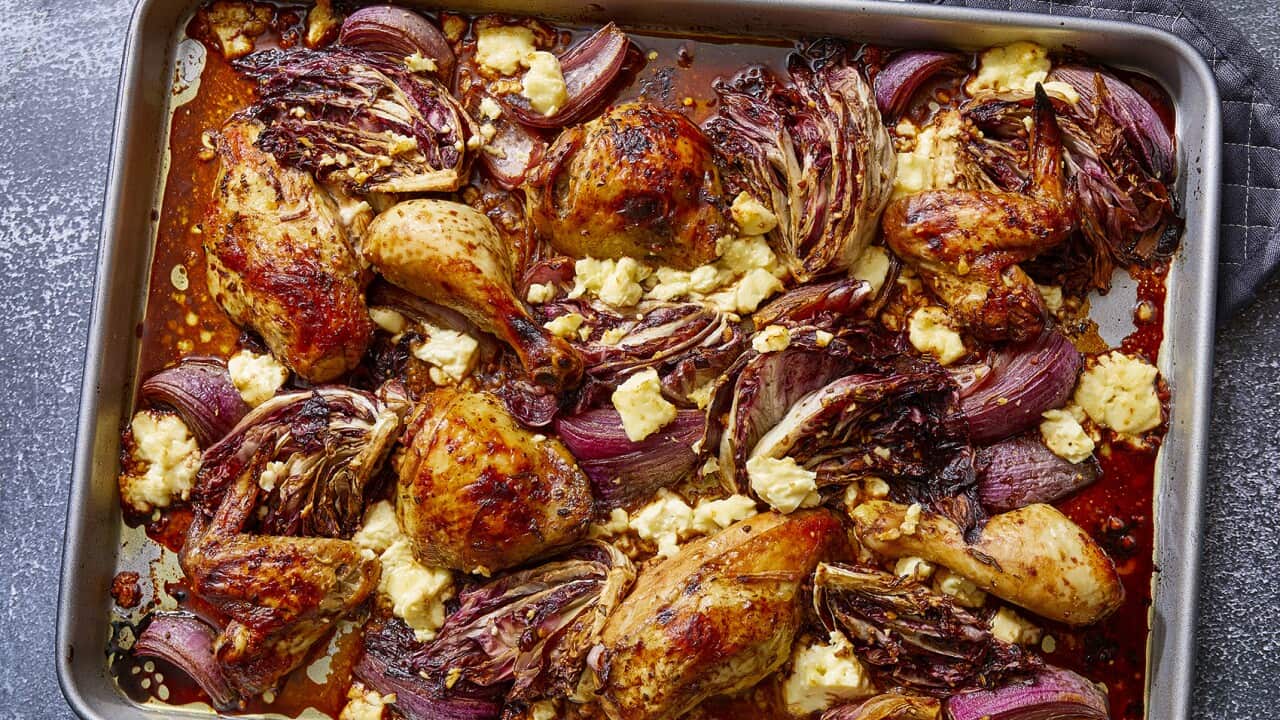 A metal baking tray holds a colourfal spread of roast chicken, red onion, radiccio and feta.