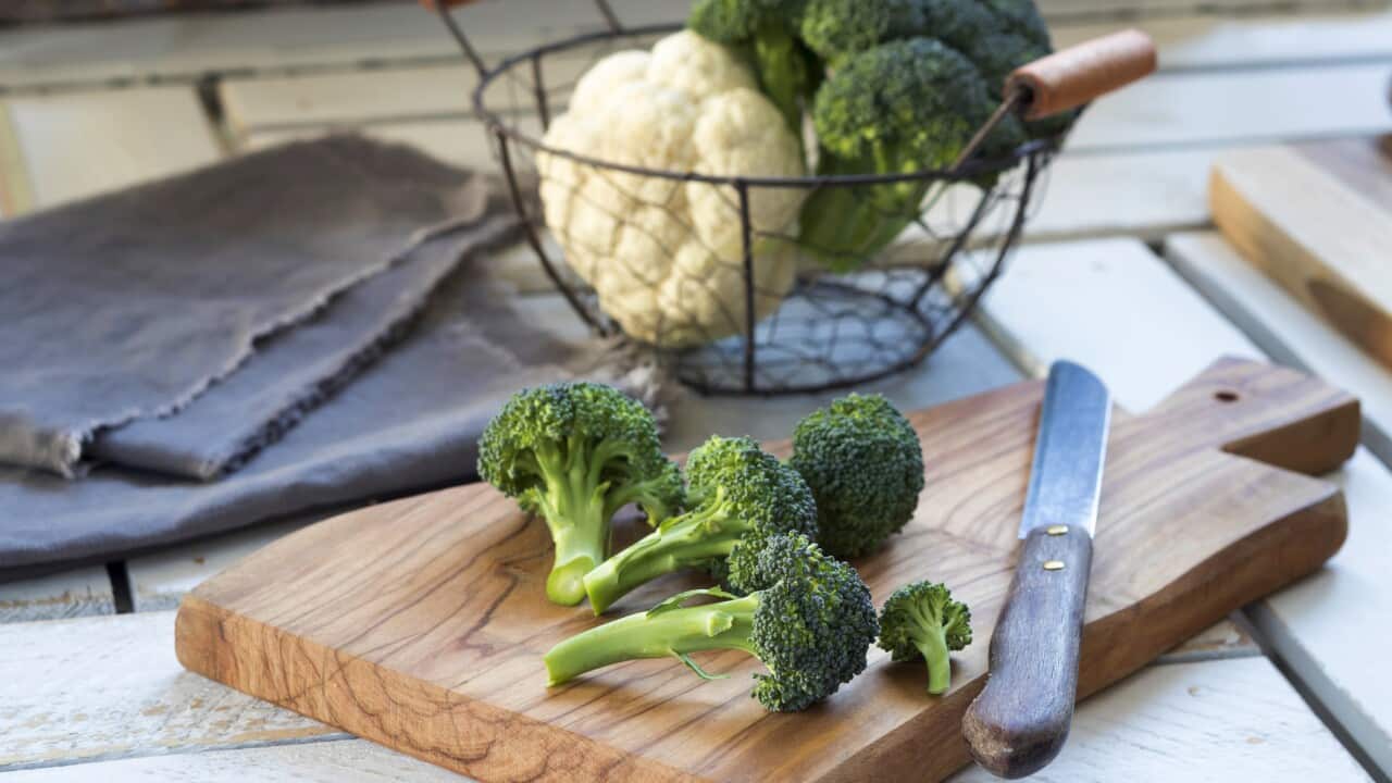 Broccoli florets and kitchen knife on wooden board