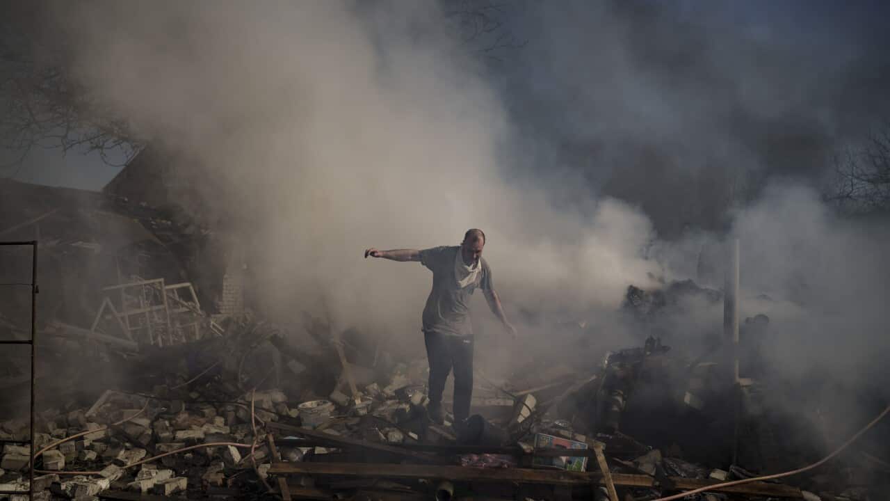 A man walks on the debris of a burning house, destroyed after a Russian attack in Kharkiv, Ukraine, Thursday, March 24, 2022. (AP Photo/Felipe Dana)