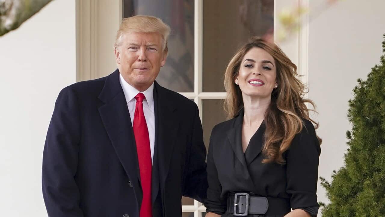 Donald Trump stands next to a woman in a black outfit.