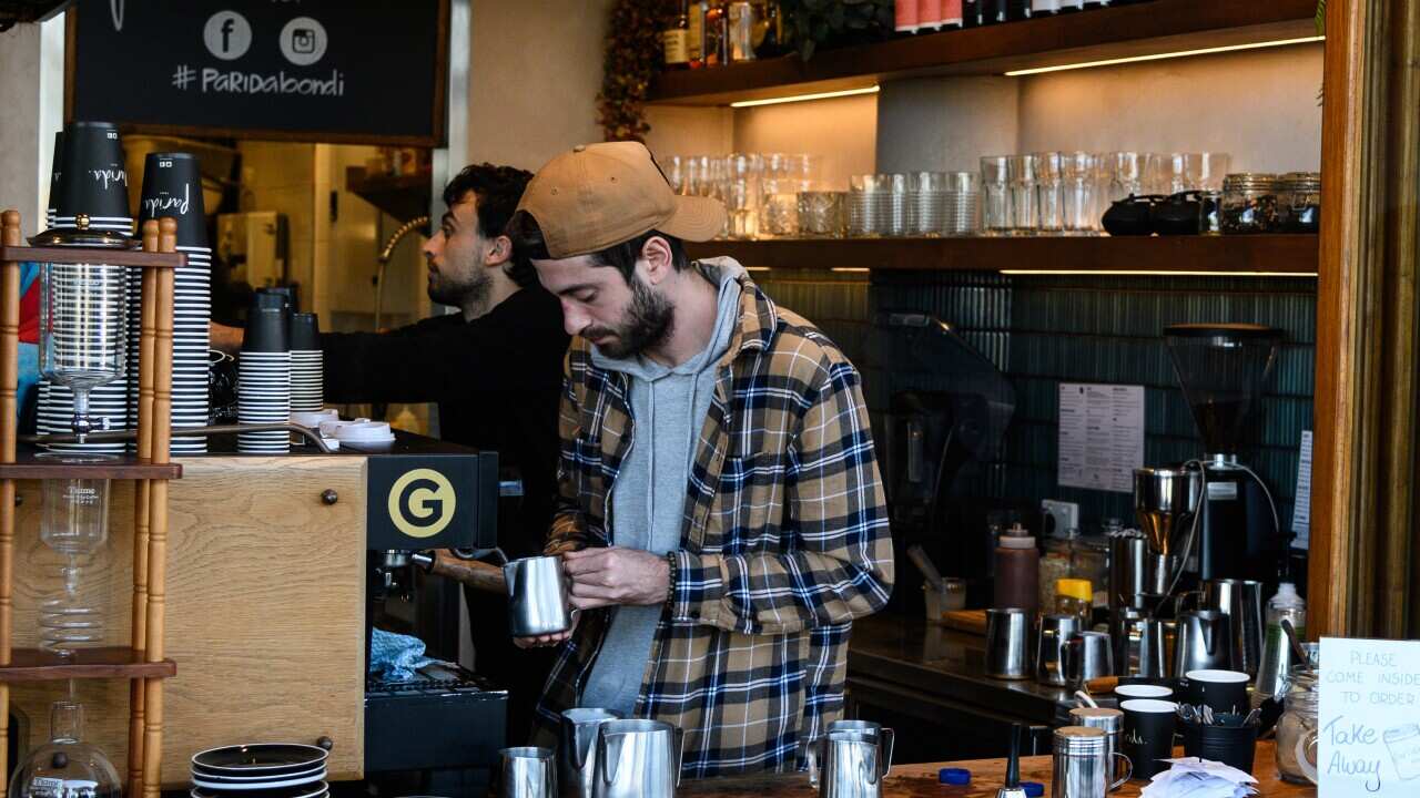 A barista working at a cafe wearing a flannel shirt