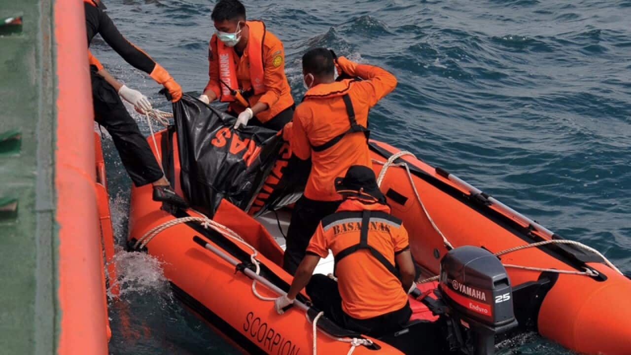 Indonesian rescuers removing the body of a victim of flight QZ8501