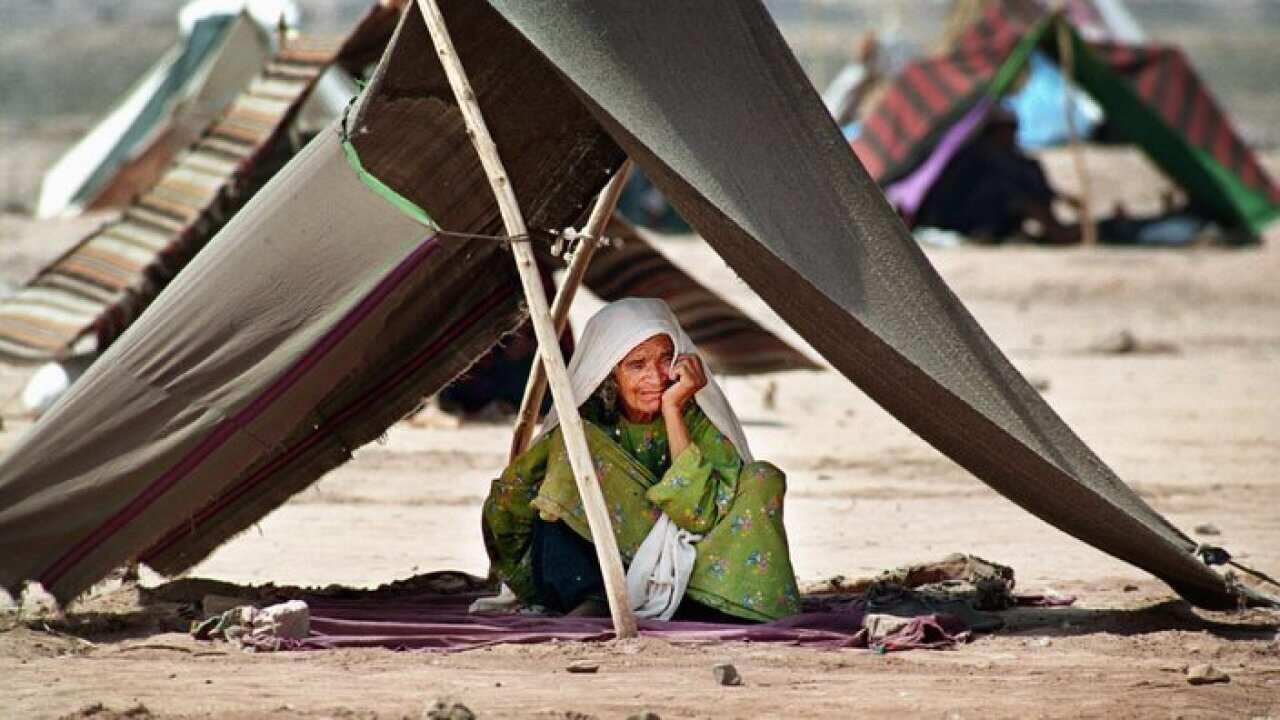 - Huddled under a makeshift tent an elderly woman waits for her family to return, June 21, 2001.