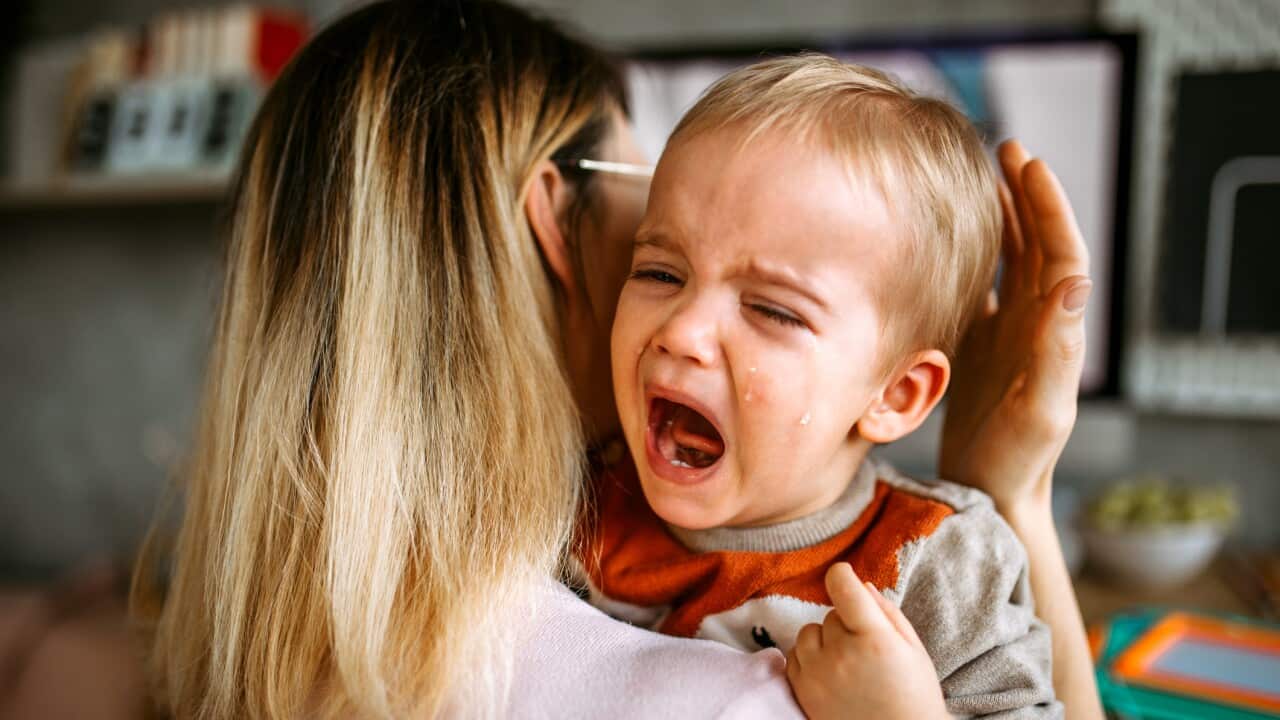 Baby boy is crying while mother holding him in arms