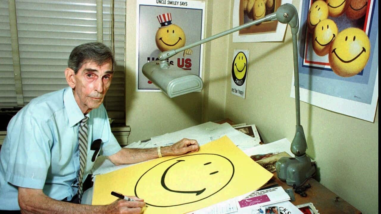 Smiley face creator Harvey Ball, of Worcester, Mass., autographs posters of the internationally recognized symbol for good cheer in his office on Monday, July 6, 1998 in Worcester, Mass.