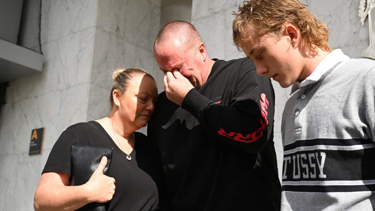 Three people standing next to each other, one of them is crying