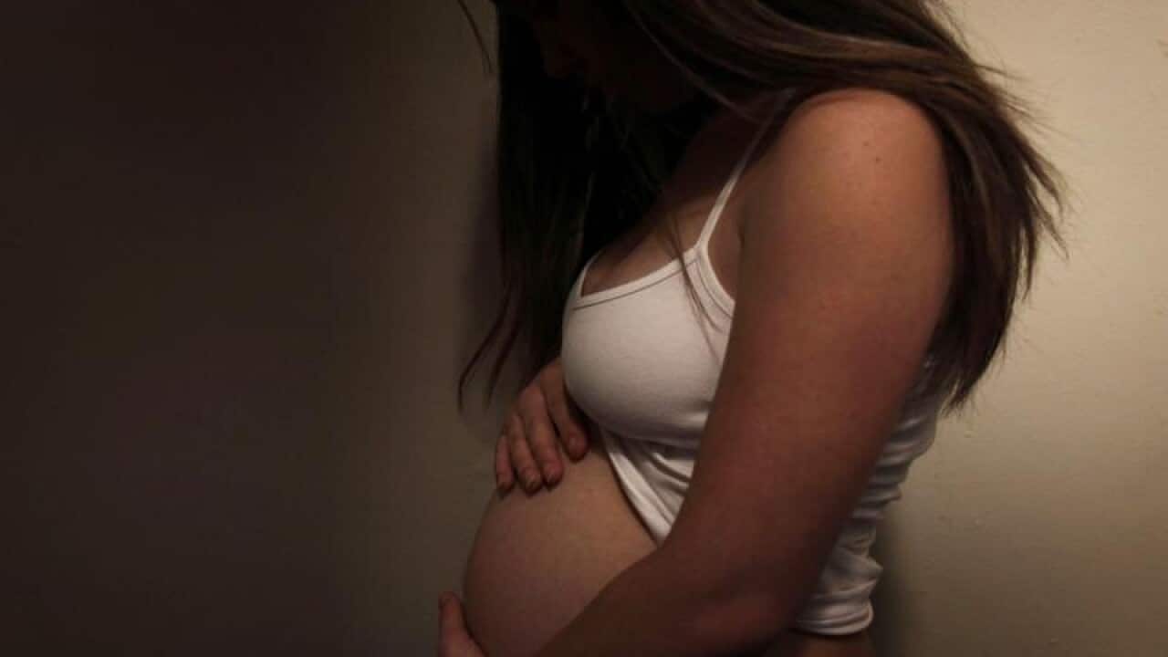 A pregnant woman displays her belly