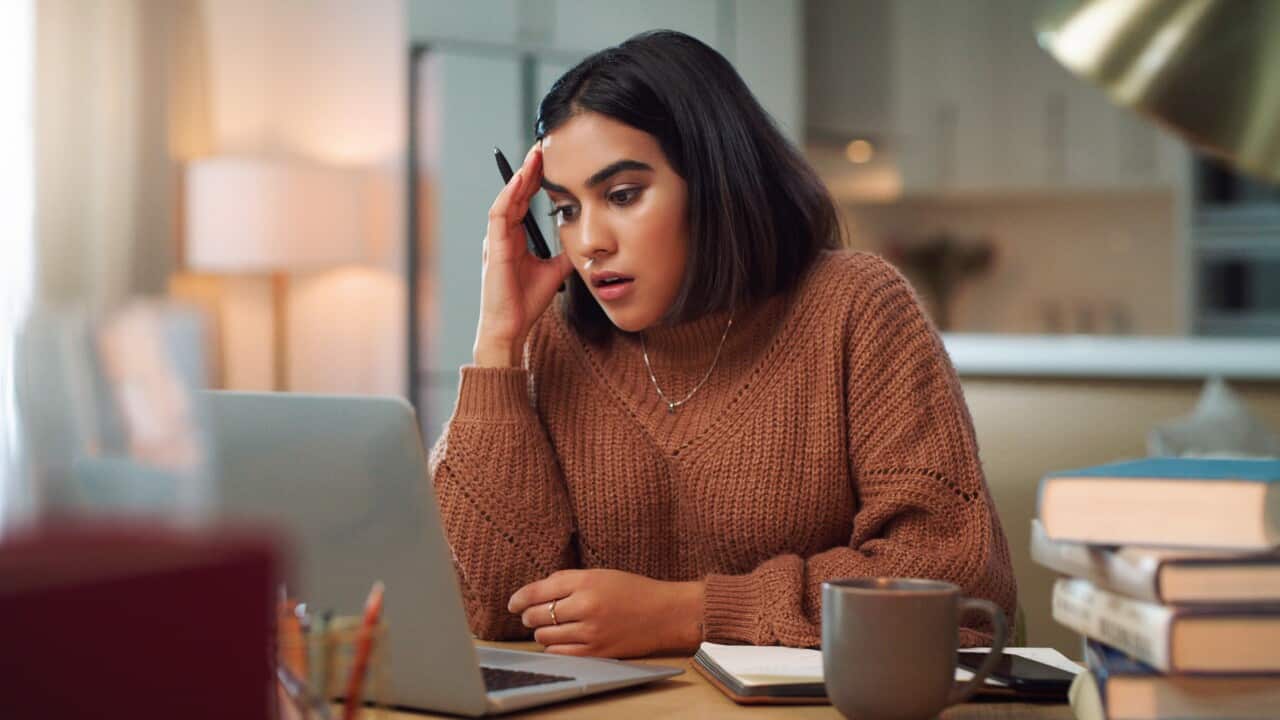 Shot of a young woman looking stressed out while using a laptop to study at home