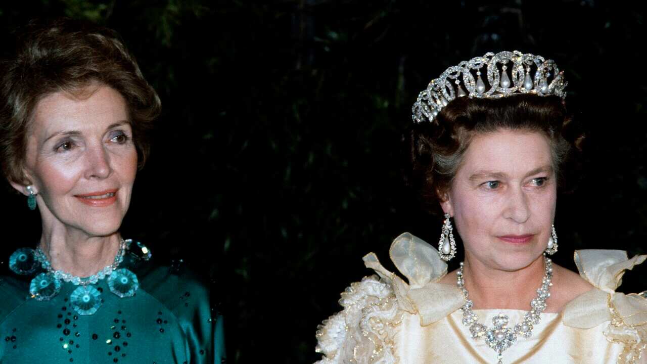 Nancy Reagan (left) and Queen Elizabeth II (wearing a tiara) standing next to each other.