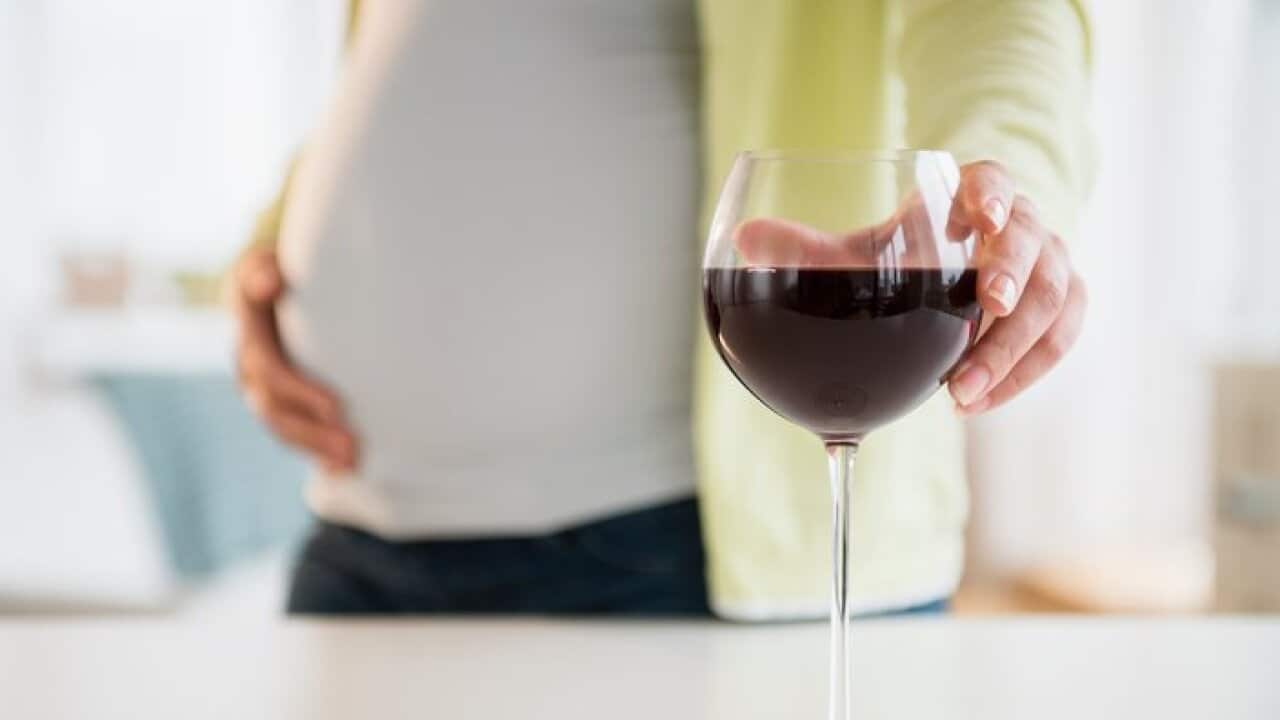 Pregnant woman with glass of red wine