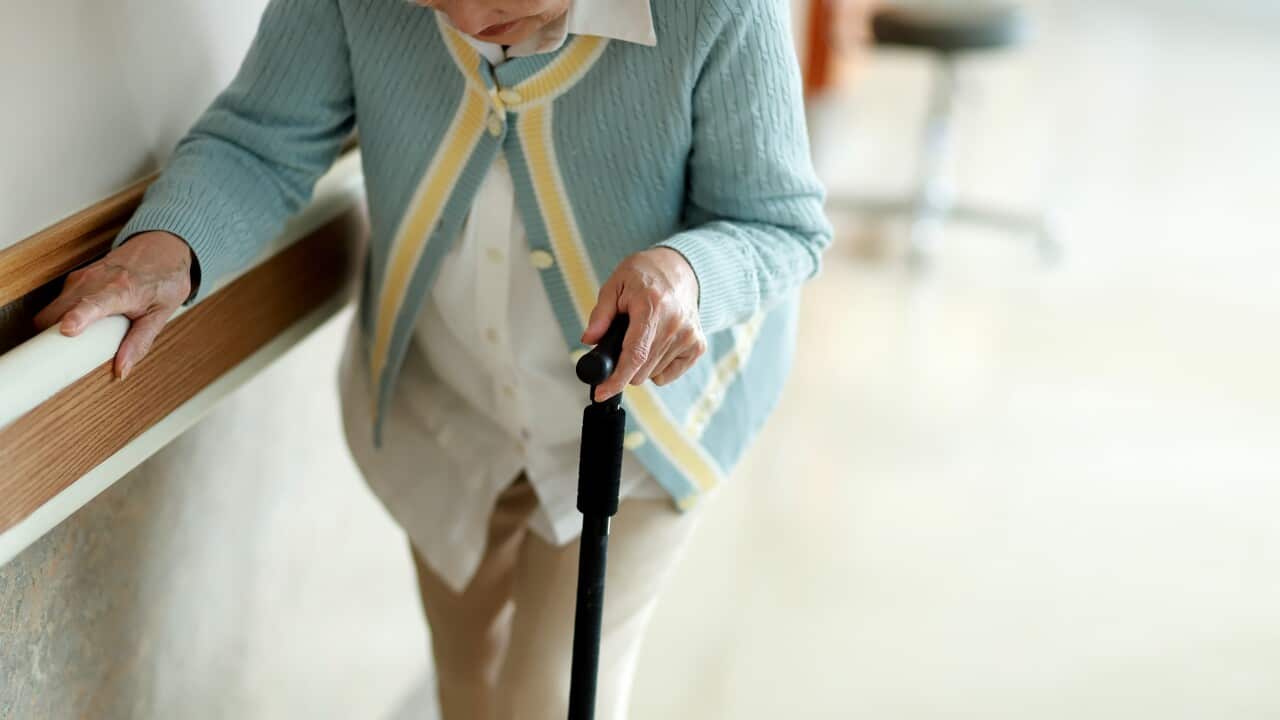 Senior woman walking with walking cane in hospital corridor
