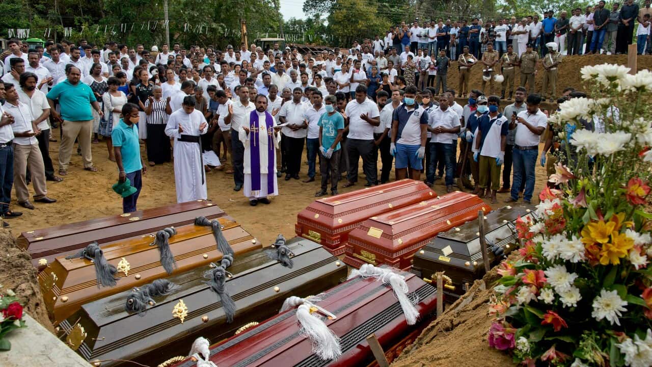 A priest conducts religious rituals during a mass burial for Easter Sunday bomb blast victims in Negombo, Sri Lanka.