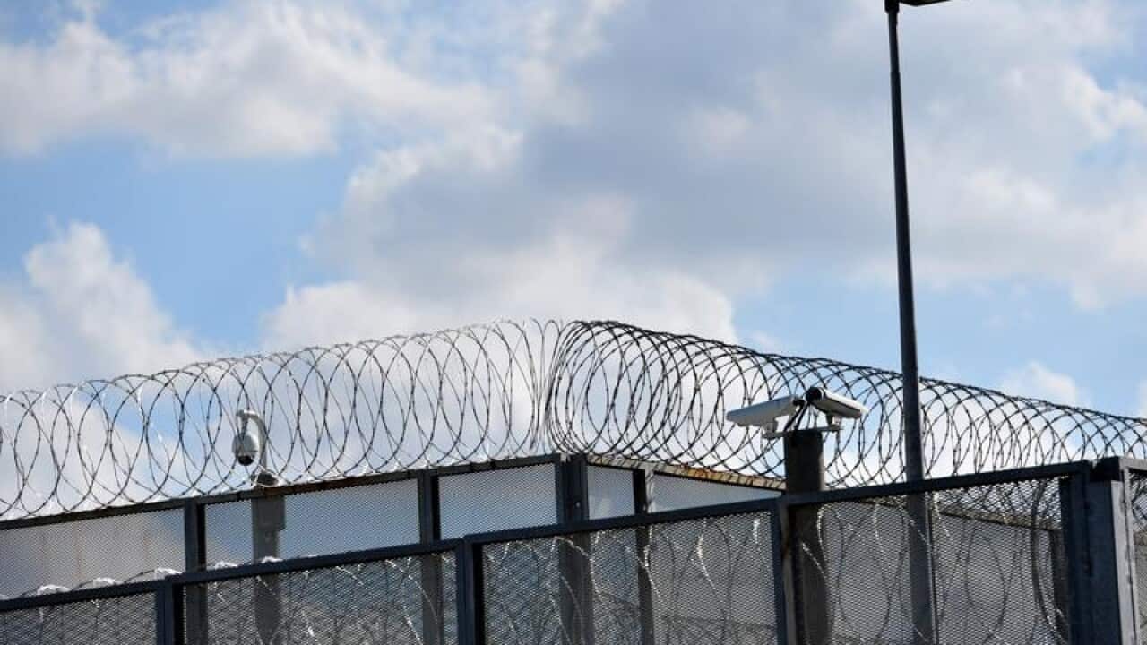 Rerimeter fence at a jail with barbed wire, cameras and lights