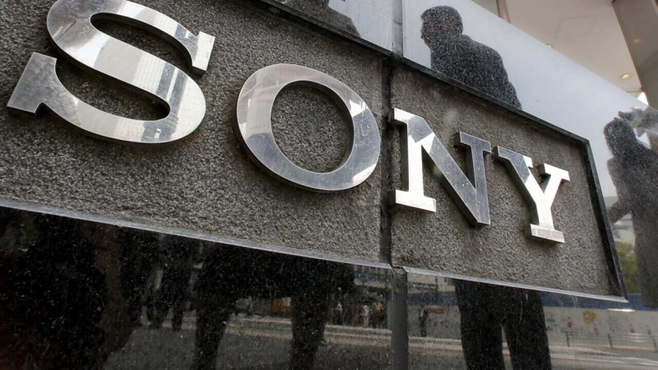People are reflected on a wall of the Sony building in Tokyo