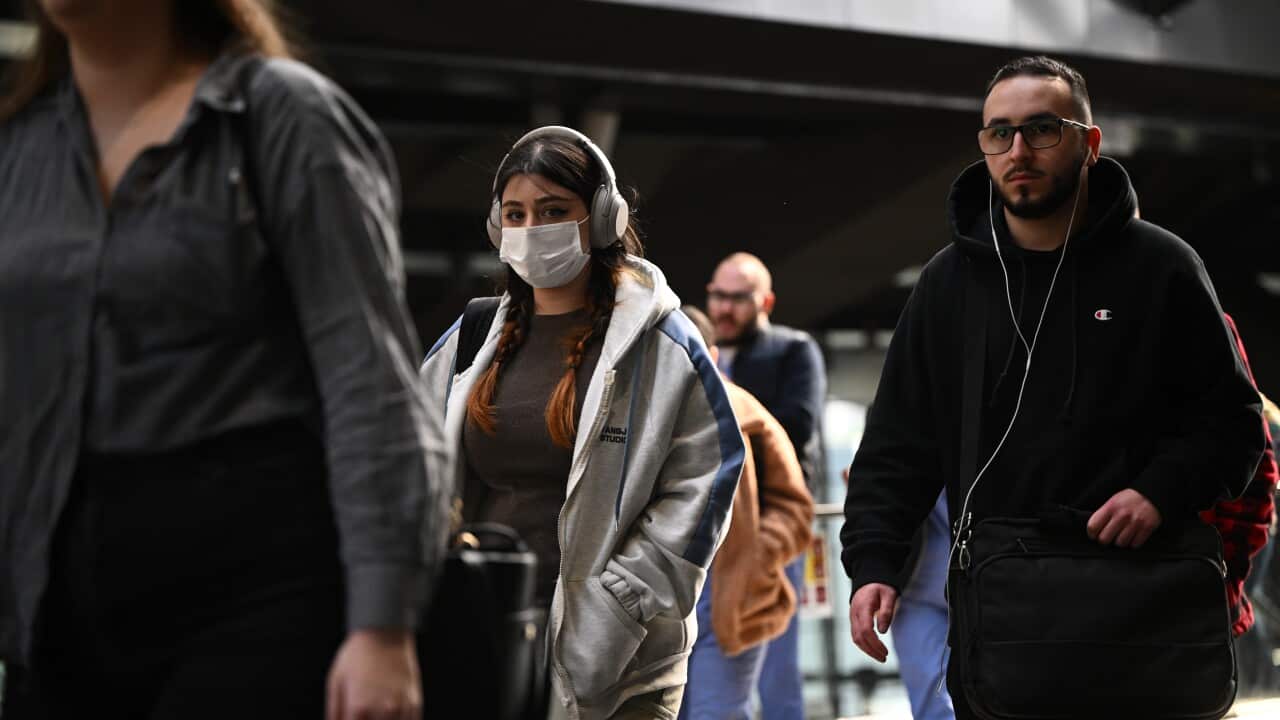 People wearing face masks walk near a station