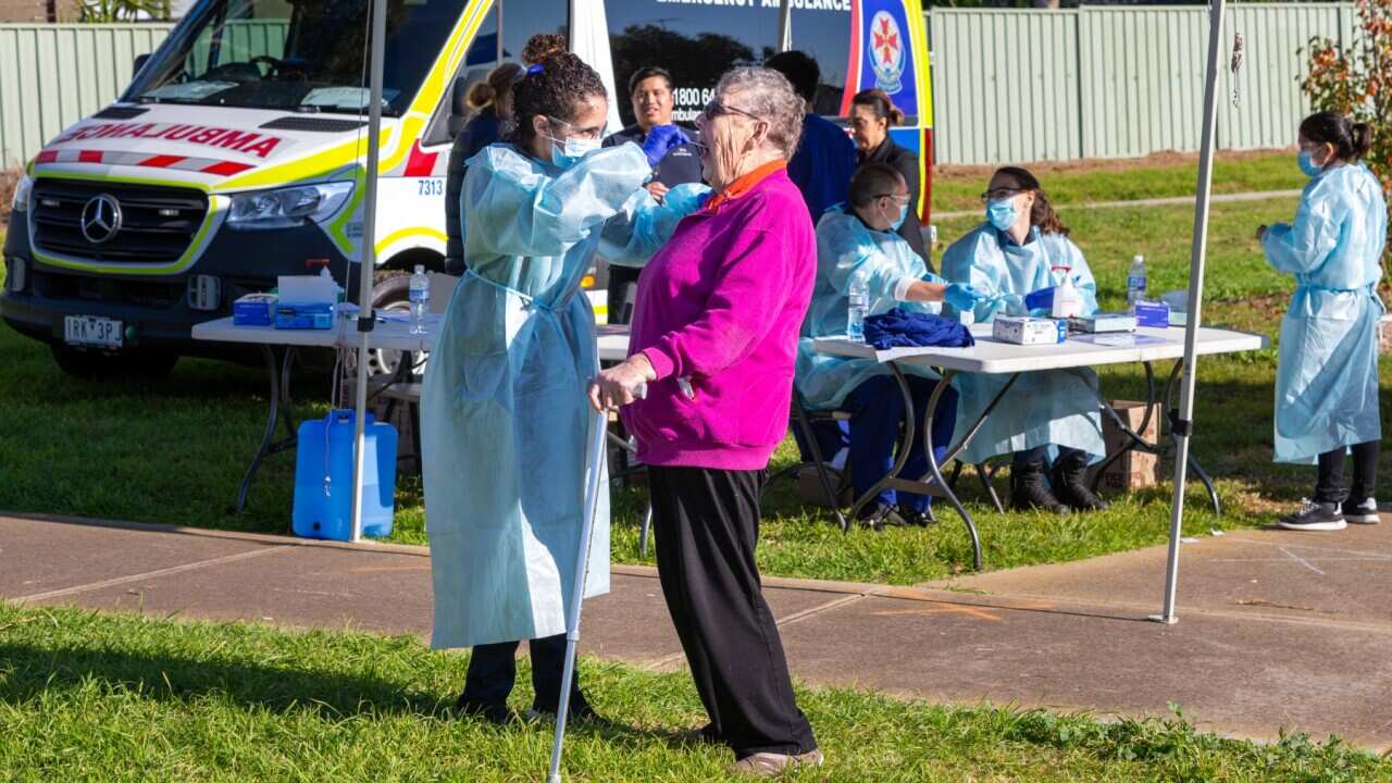 elderly woman tested for coronavirus by healthcare worker in outdoors testing site.