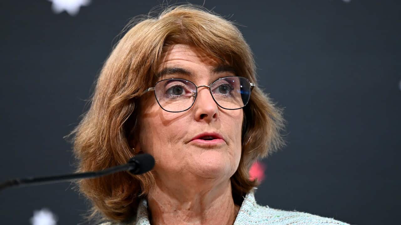 A woman with brown hair and black-rimmed glasses