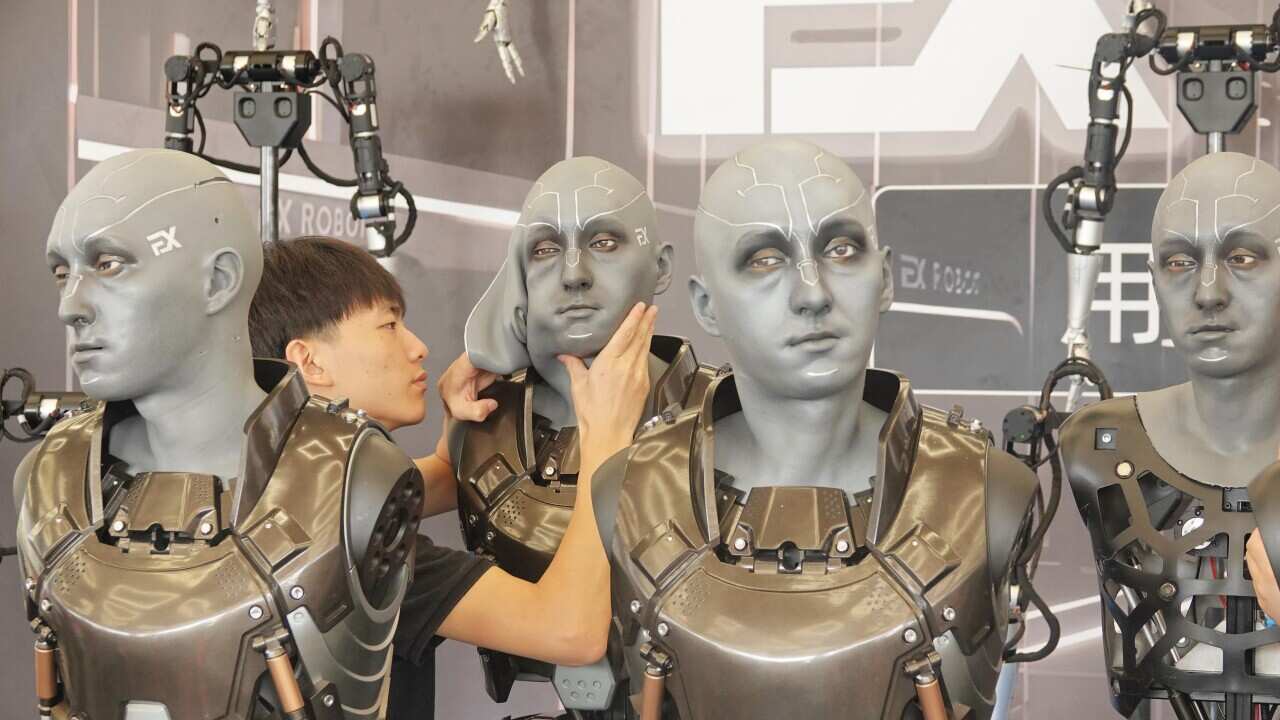 A man adjusts a robot's face.