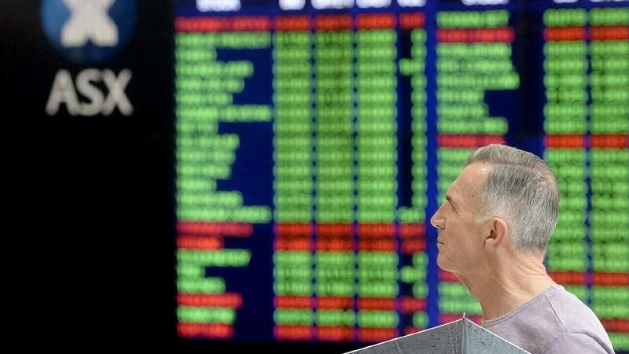 Pedestrians are seen reflected on the ASX trading board in Sydney.