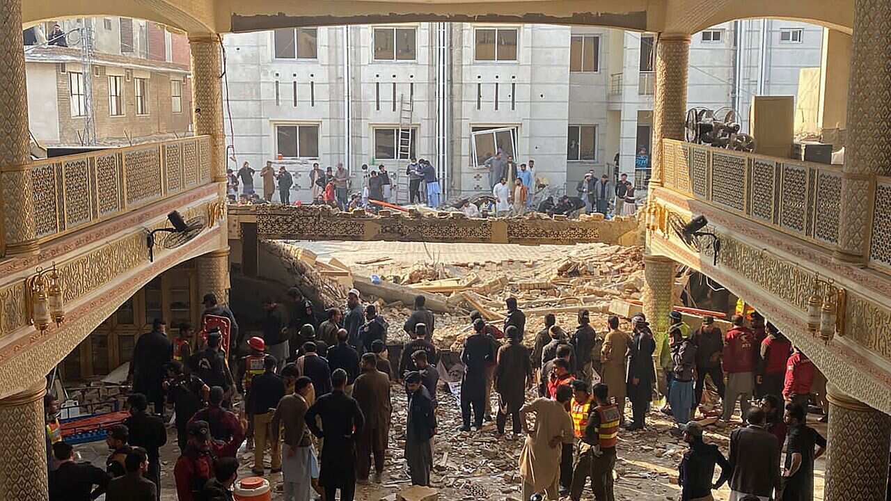 People look at the destruction of a mosque.