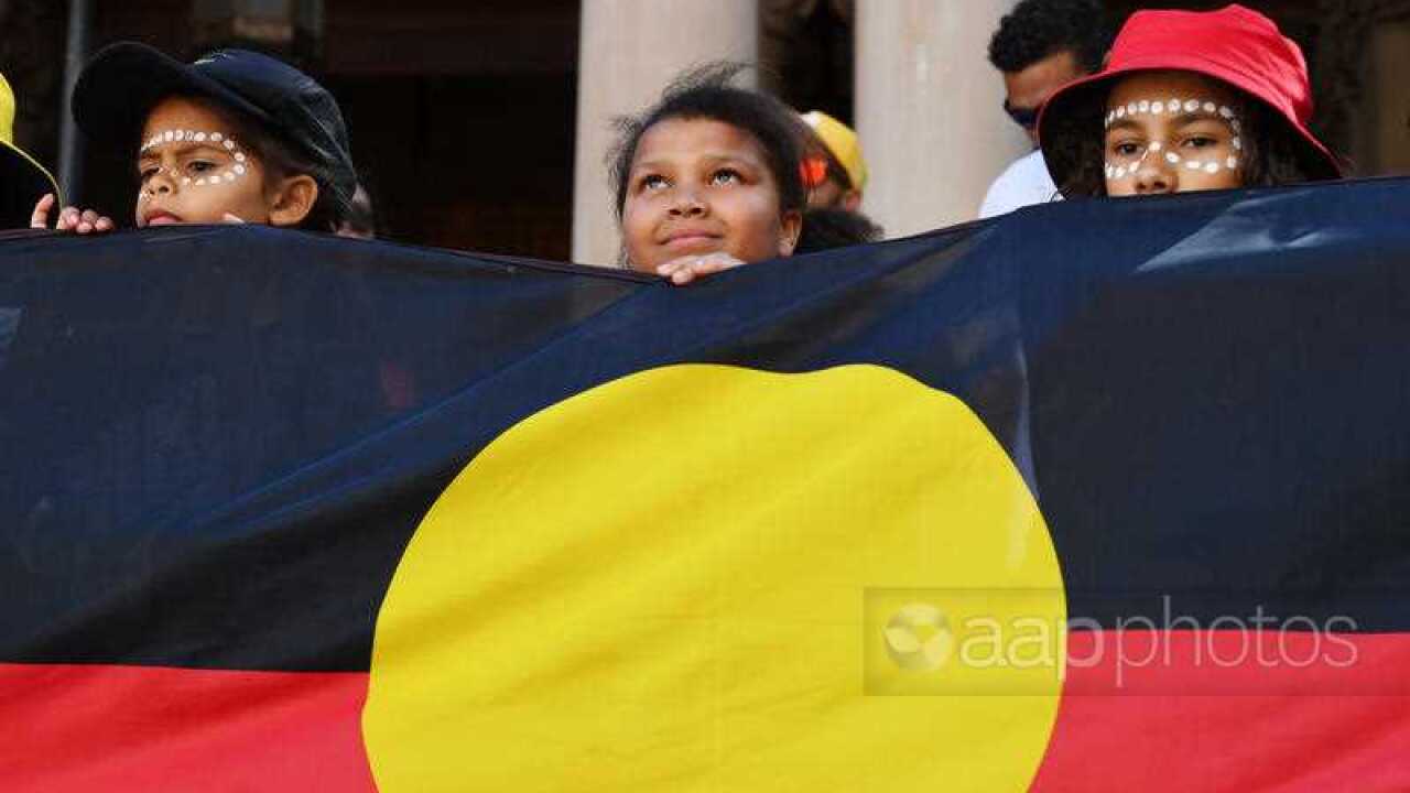 Gözaltında ölümleri protesto için Sydney yapılan yürüyüşte, Town Hall önünde Aborijin bayrağını tutan çocuklar.