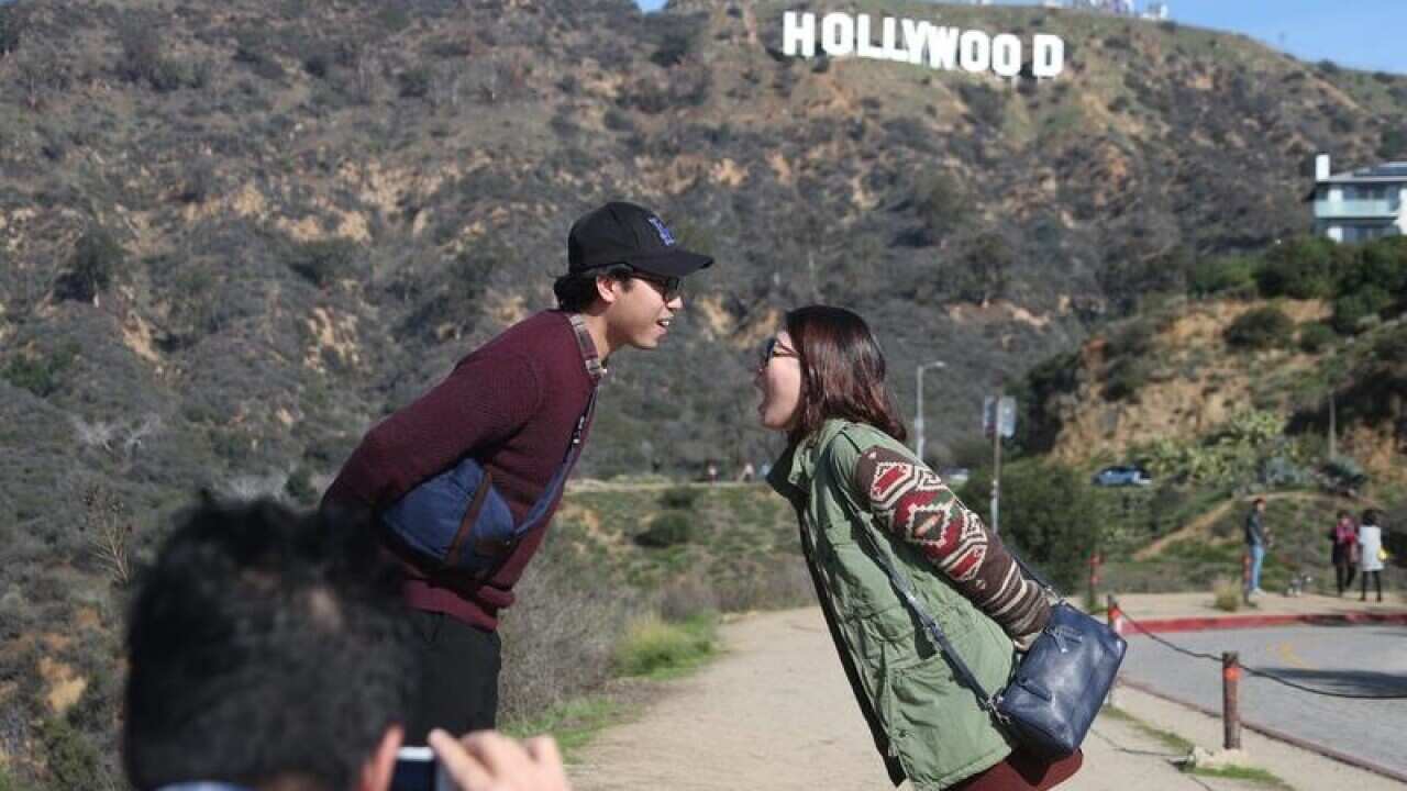 Tourists pose before the Hollywood sign