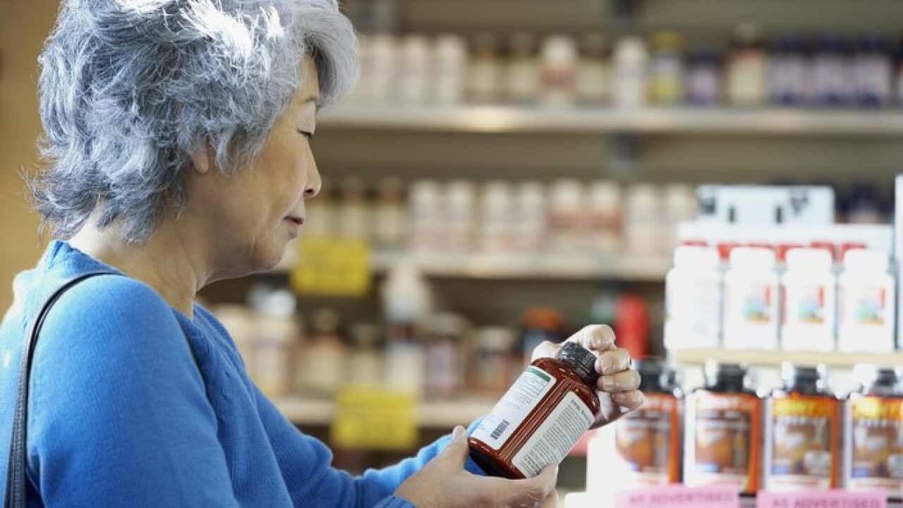 Senior Asian woman reading vitamin label