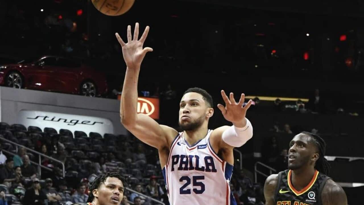 Philadelphia 76ers guard Ben Simmons shoots flanked by Atlanta Hawks.