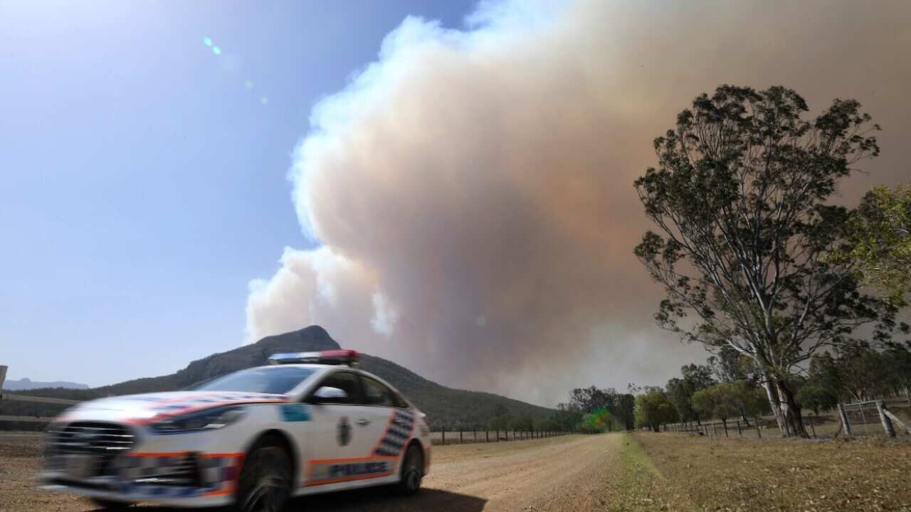 A police vehicle is seen as smoke from an out-of-control bushfire billows in the distance near Clumber, Queensland