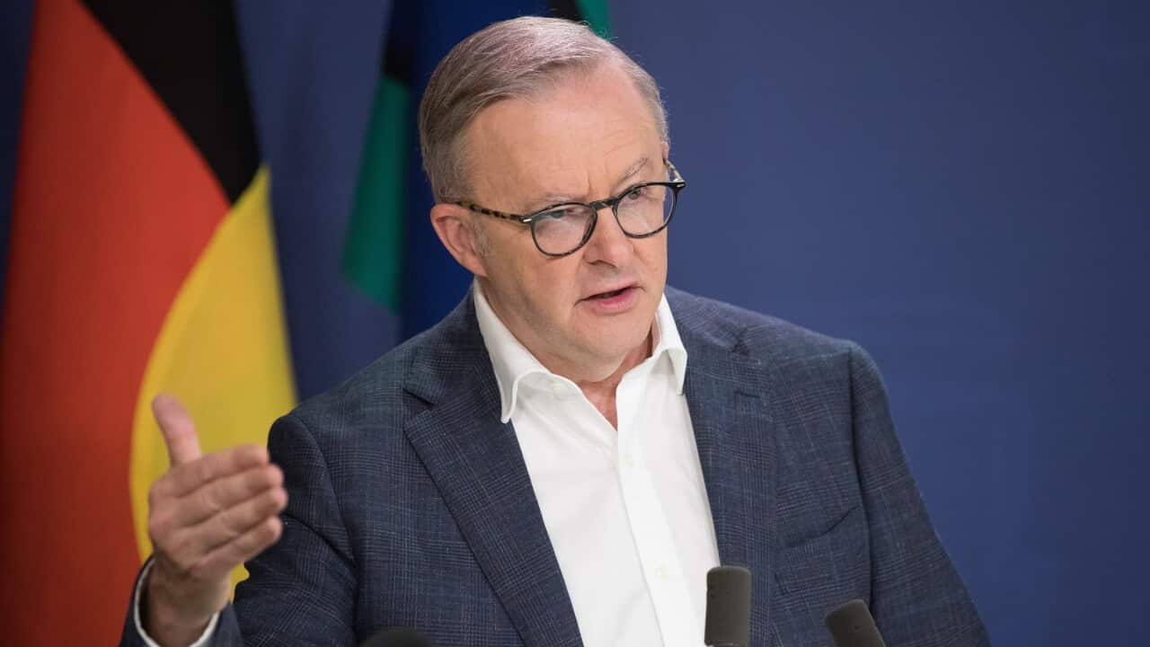 Anthony Albanese gestures with his right hand as he speaks in front of a microphone.