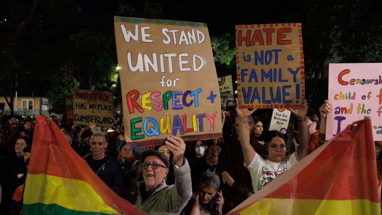 Protesters holding placards and rainbow flags