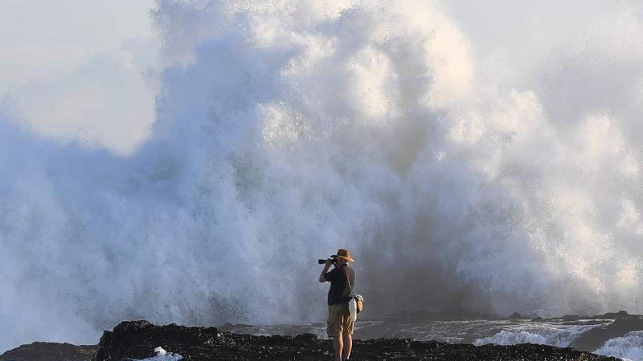 A photographer photographs large surf conditions on the Gold Coast