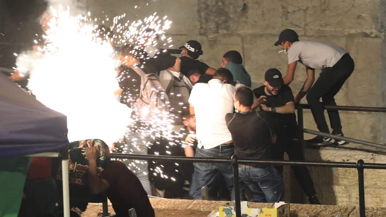 Palestinians run from Israeli police stun grenade during a protest in Jerusalem, 7 May 2021