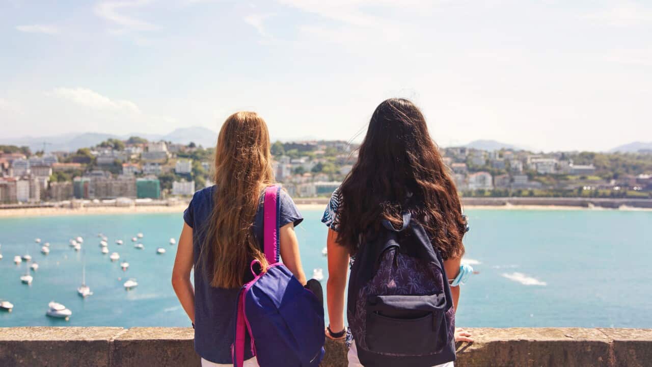 Teenage girls with backpack looking at the sea