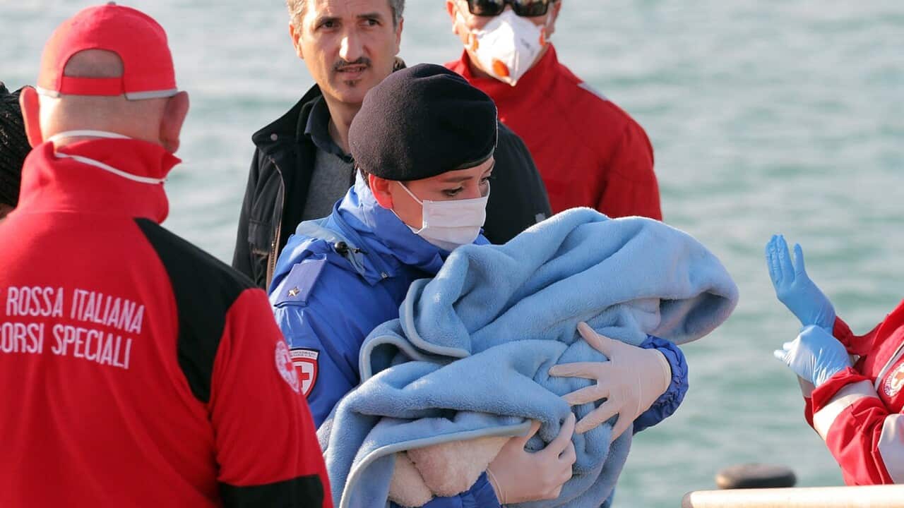 A Red Cross officer carries a baby after migrants disembarked at the Sicilian Porto Empedocle harbor, Italy, Monday, April 13, 2015. (AP Photo/Calogero Montanalampo)