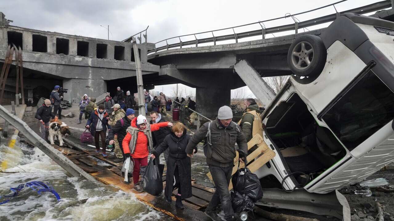 People cross an improvised path under a destroyed bridge while fleeing the town of Irpin close to Kyiv