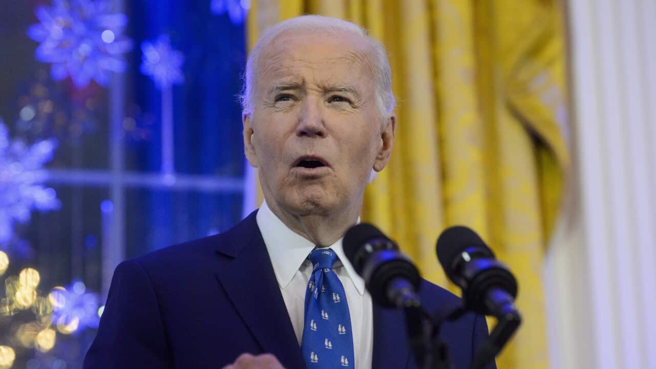 Joe Biden points with his index finger while speaking into a lectern microphone with the US coat of arms on the front.